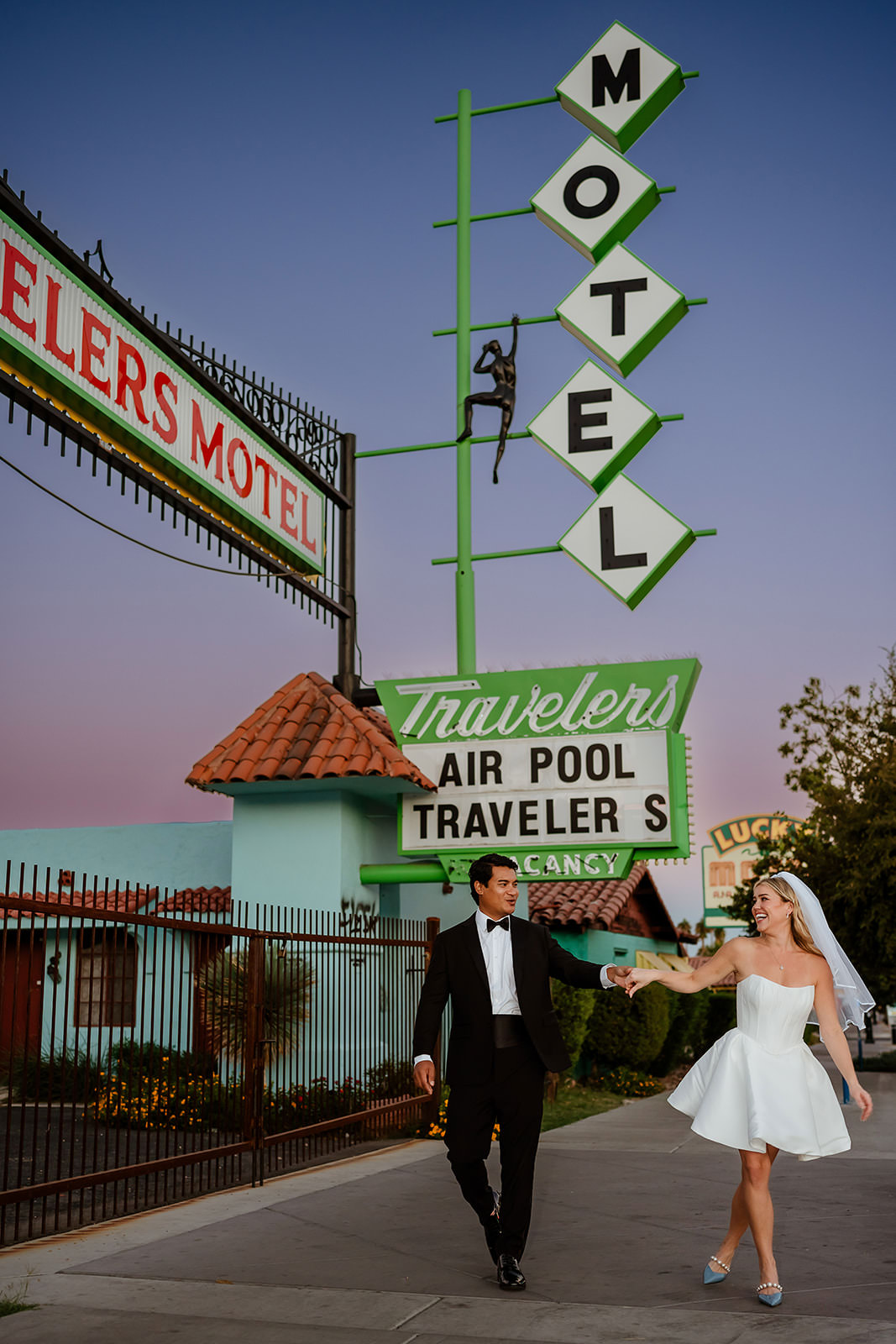 wedding couple walking under Travelers Motel sign in Las Vegas at sunset